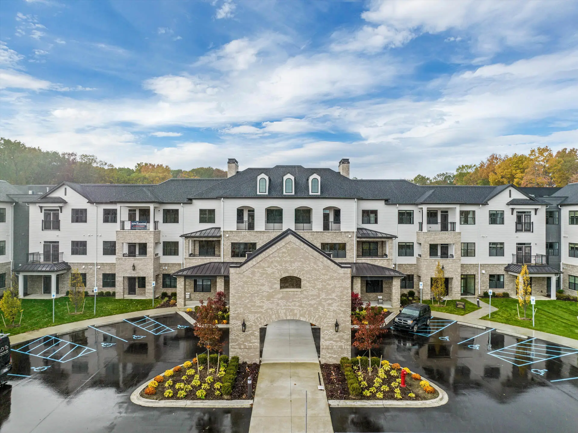 Front exterior of a multi-story senior living community with landscaped entrance and covered drive.