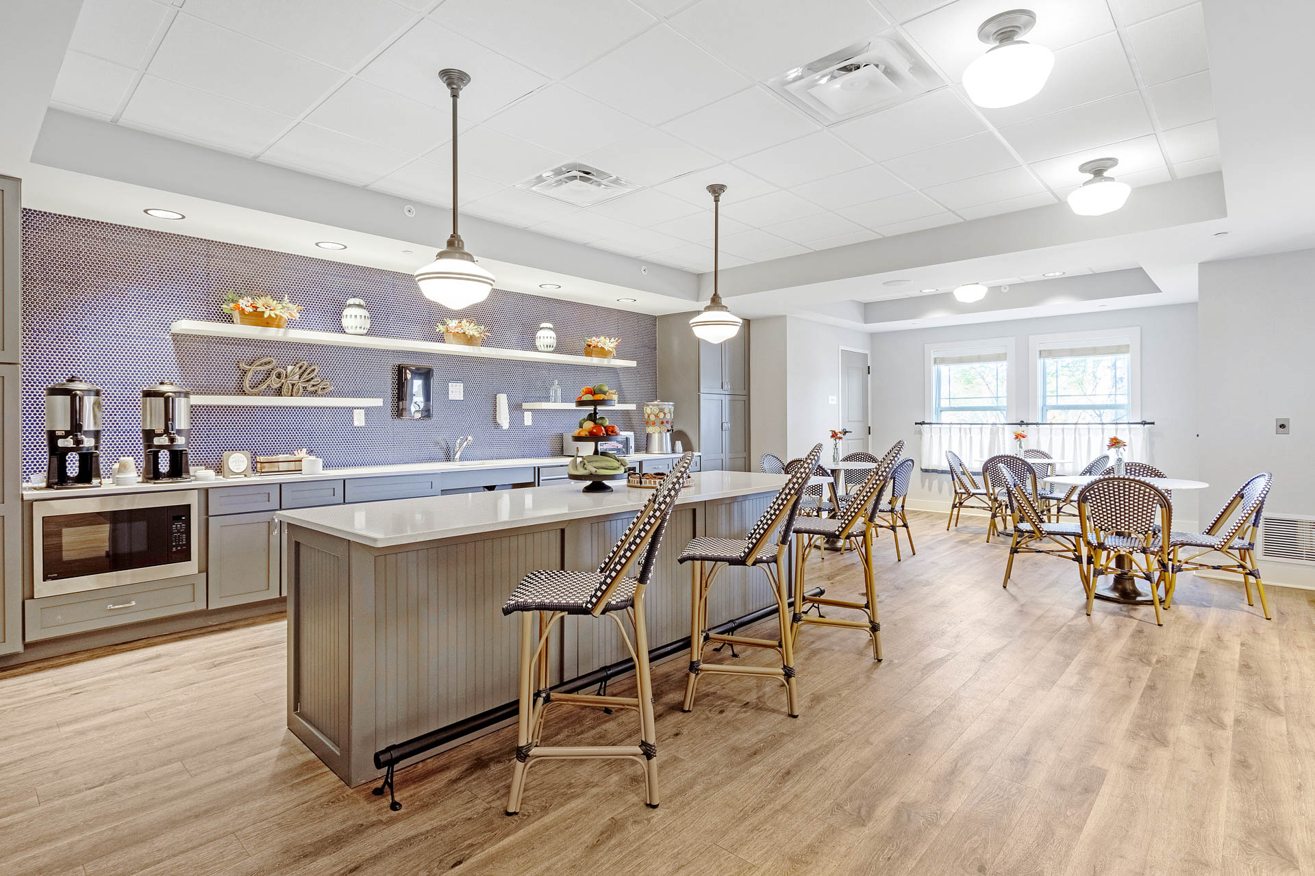 Bright senior living bistro with coffee station, counter seating and café tables.