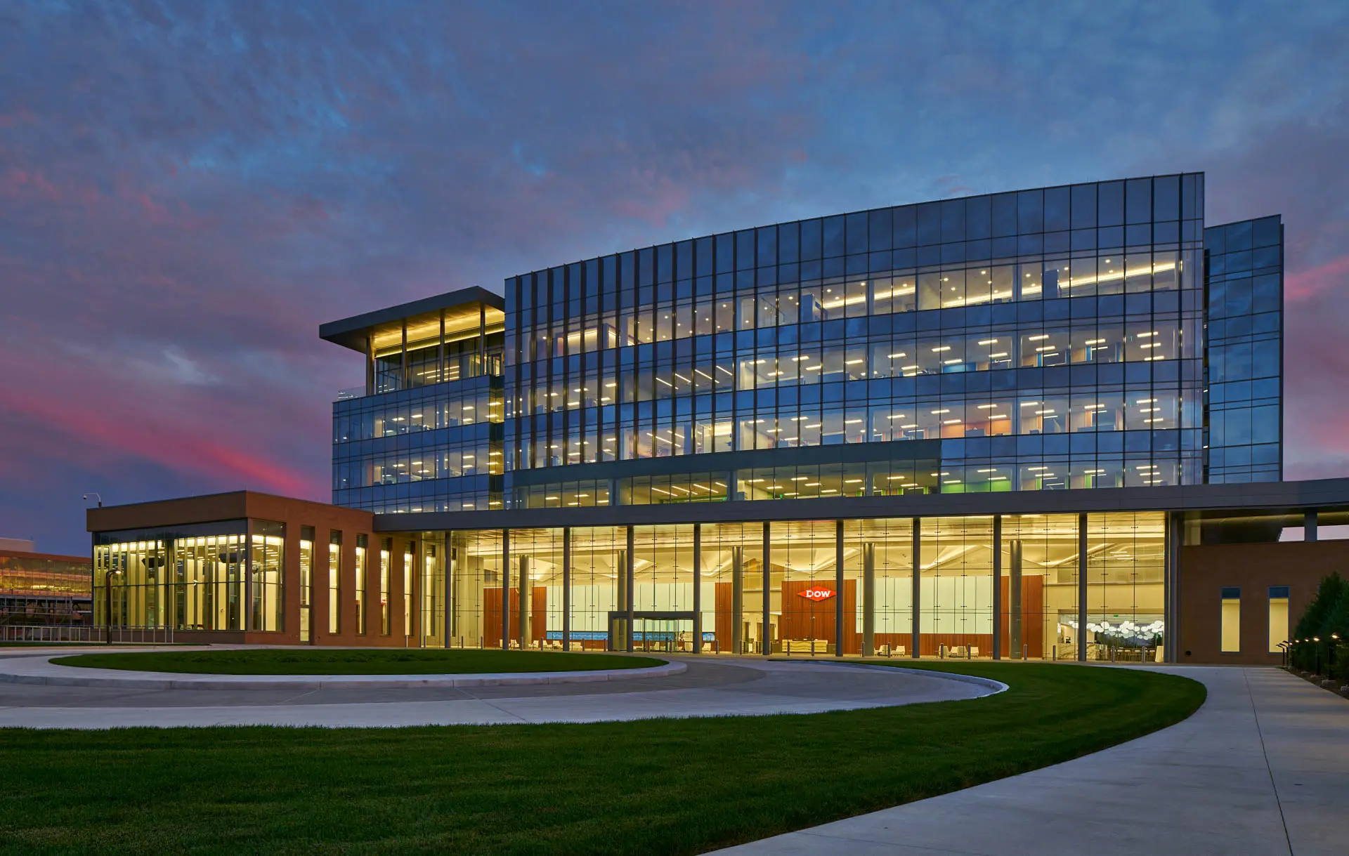 Modern Dow corporate headquarters with illuminated glass façade at dusk.