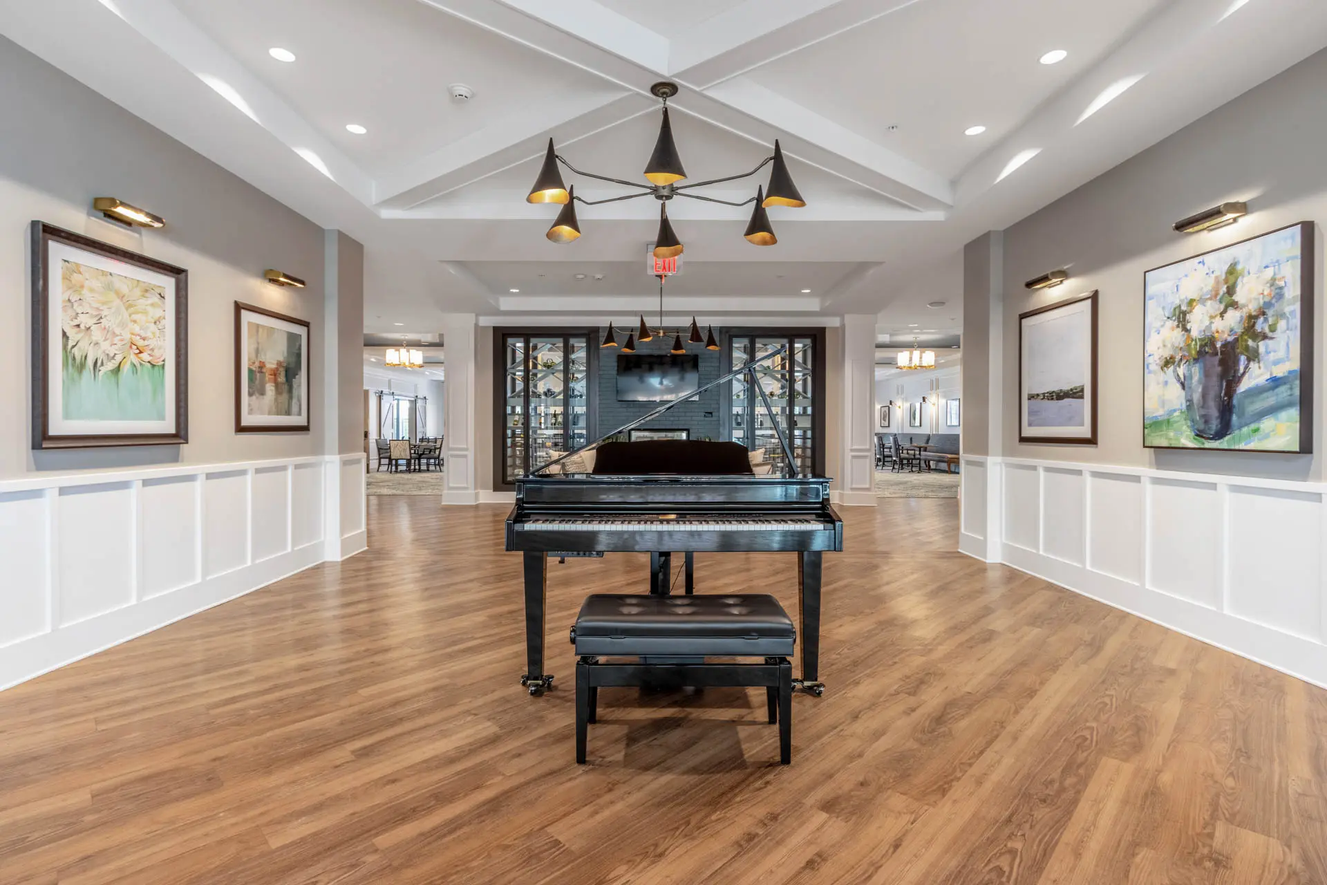 Senior living lobby with grand piano, wood flooring and framed artwork.