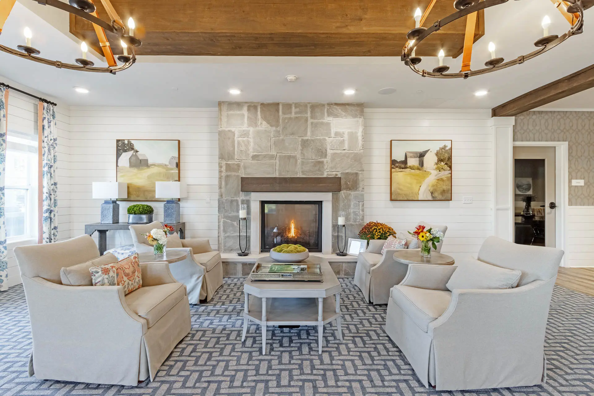 Senior living lounge with stone fireplace, upholstered seating and rustic wood details.
