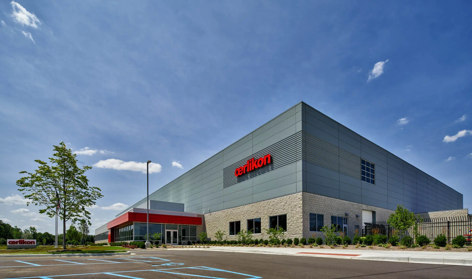 Oerlikon industrial facility with modern metal façade, stone exterior and landscaped entrance.