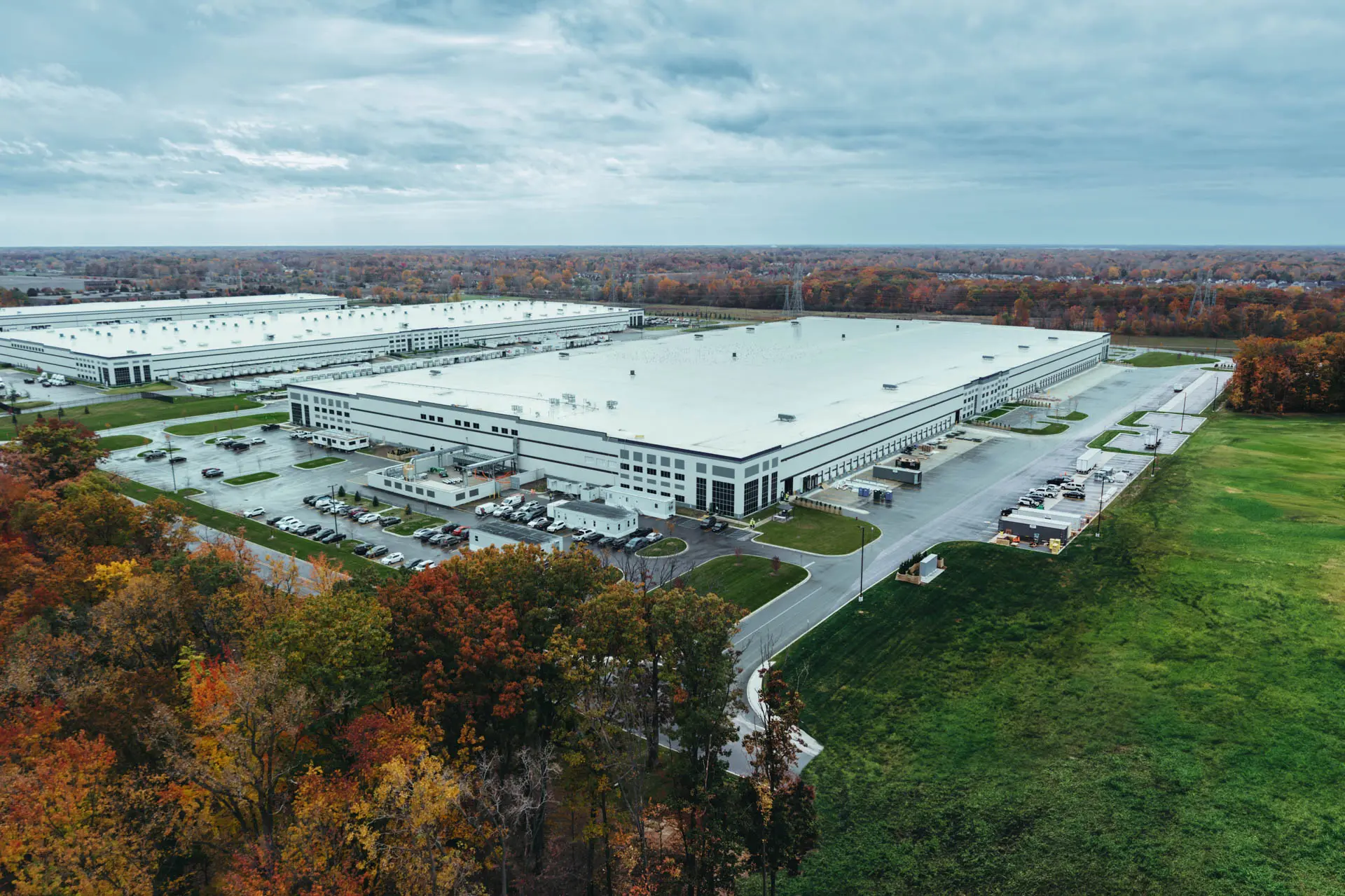 Aerial view of a large industrial facility surrounded by autumn trees and open land.
