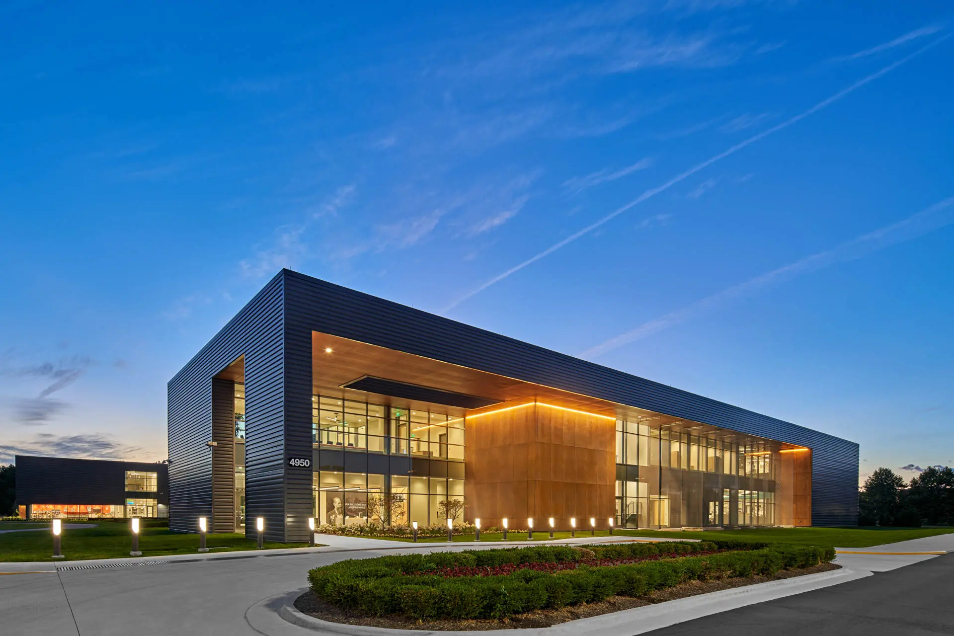 Modern corporate and research facility with glass façade and illuminated entrance at dusk.
