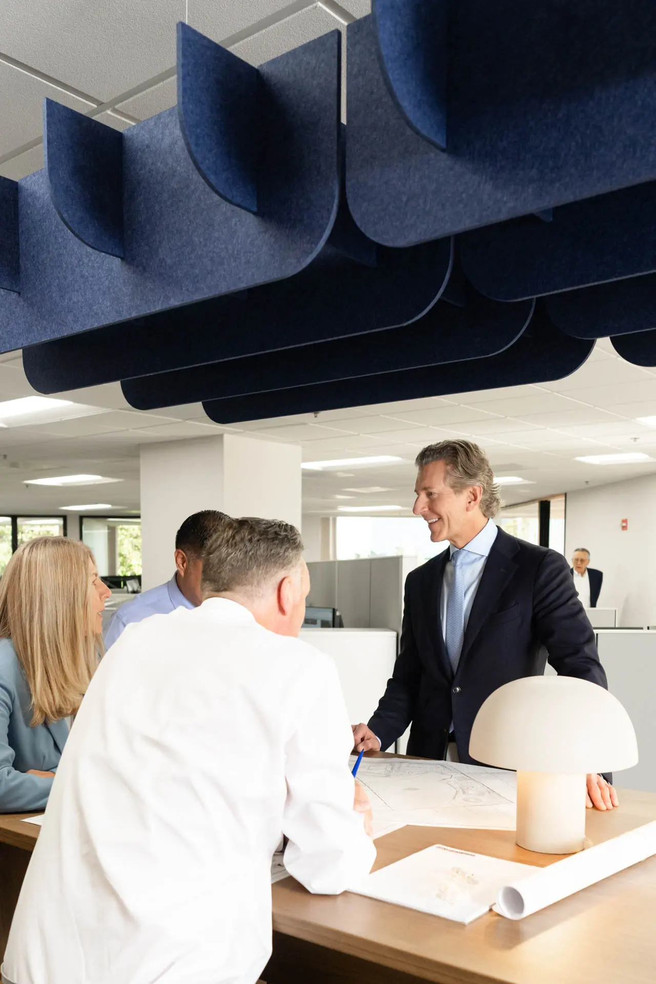 Business professionals collaborating around architectural plans in a modern office.